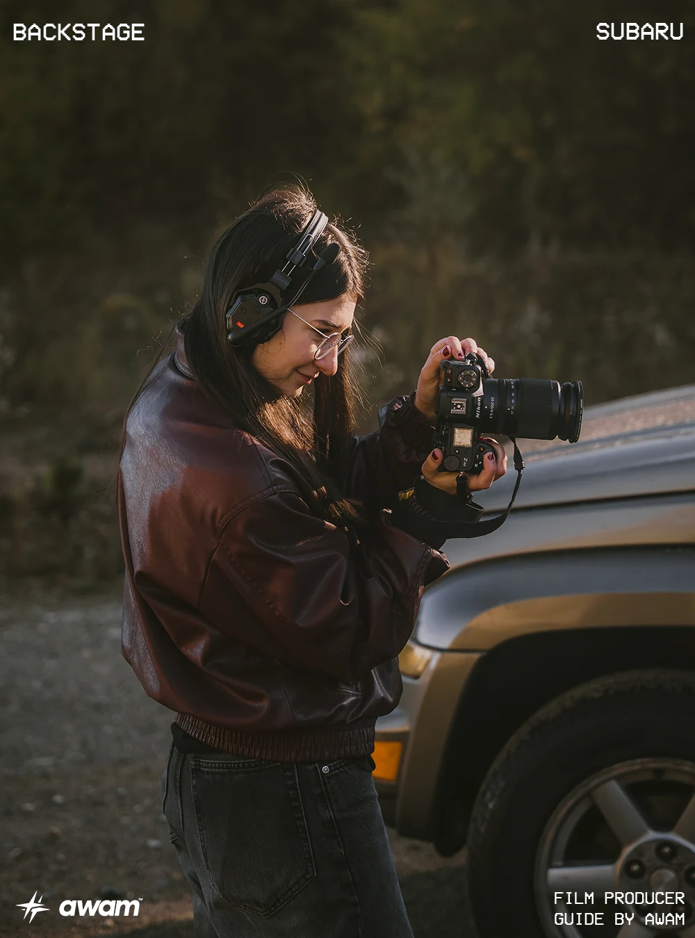 awam on set: a photographer with headphones checks a camera beside a vehicle at dusk
